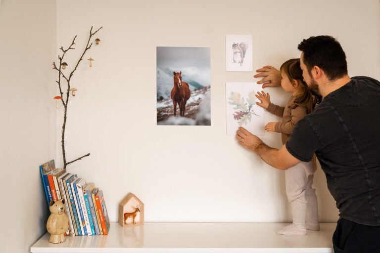 Father and daughter decorating a wall with posters, creating a warm and personal home decor with wall art.