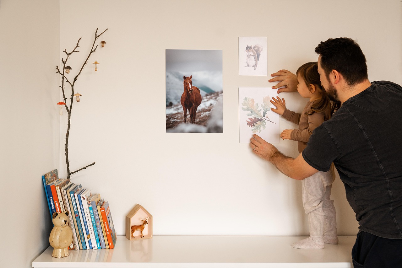 Father and daughter decorating a wall with posters, creating a warm and personal home decor with wall art.